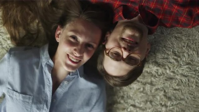 Happy Smiling Young Couple Laying on The Floor. Top view. Casual Lifestyle.