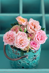 Beautiful fresh pink roses in a vase on a blue background . 