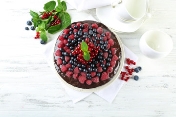 Delicious chocolate cake with summer berries on wooden table, top view