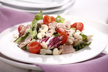 delicious salad with tuna and cashew nuts on a white plate 