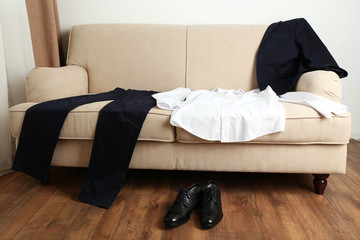 Male clothing on sofa near shoes on floor in room