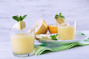 Glasses of melon cocktail on white wooden background