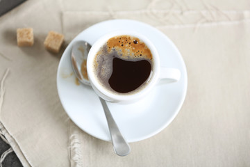 Cup of flavored coffee with lump sugar on table with napkin, closeup