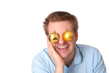 Junger lachender Mann mit Christbaumkugeln vor den Augen