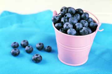 Tasty ripe blueberries in bucket on table close up