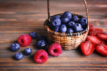 Tasty ripe berries in basket on wooden table close up
