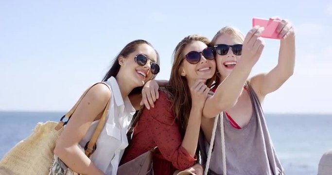Teenage girls taking selfie at beach on summer vacation