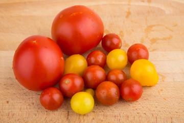 Red and yellow cherry tomatoes on a wooden cutting board