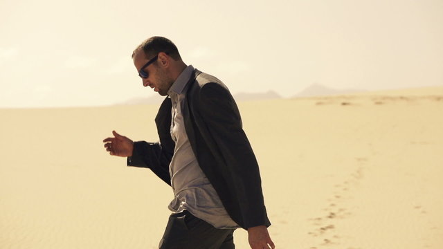 Tired, lost businessman walking through desert, slow motion shot at 240fps

