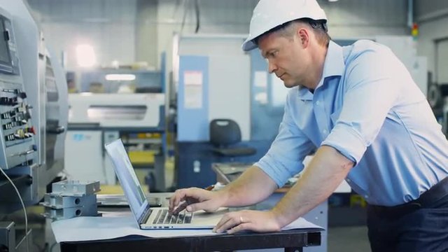 Engineer is Working on Notebook in CAD Program on Factory