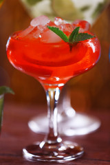 Glass of cocktail with ice on blurred lights background