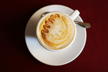 Cup of cappuccino on red napkin, top view