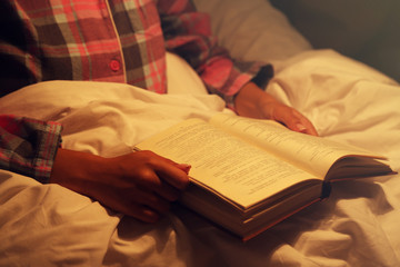 Young woman reading book in bad