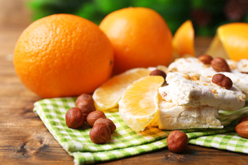 Sweet nougat with hazelnuts and oranges on table close up