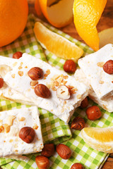 Sweet nougat with hazelnuts and oranges on table close up