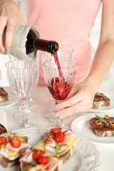 Woman pouring wine into glass, close up