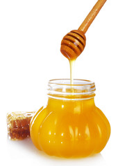 Pot of honey, wooden dipper and honeycomb isolated on white