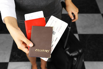 Woman with suitcase holding passports and tickets close up
