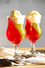 Tasty Jelly desserts with cream on light background