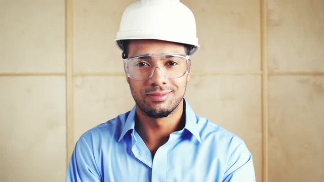 Happy hispanic foreman with arms folded at building site inspection