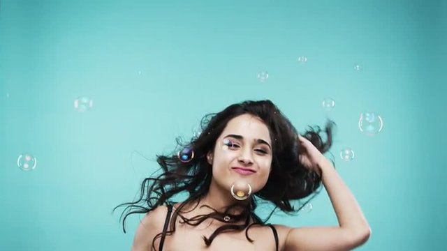 Crazy face Indian woman dancing in bubble shower slow motion photo booth blue background