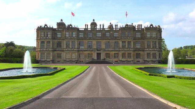 Establishing shot of the Longleat mansion in England amidst green lawns and fountains.