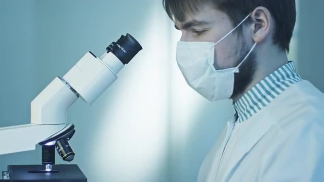 Scientist Doing Research, Looking through Microscope