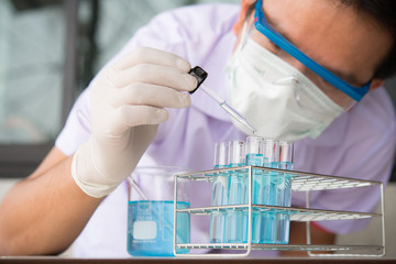 Investigator checking test tubes. Man wears protective goggles