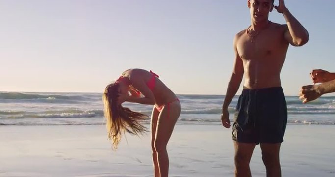 Woman flicking hair back on beach at sunrise
