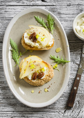 bruschetta with cheese, pear, honey and nuts on the oval plate on a light wooden surface