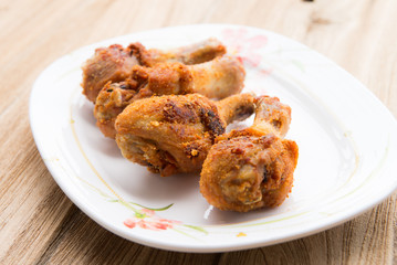 Fresh fried chicken on a white plate set on a wood table