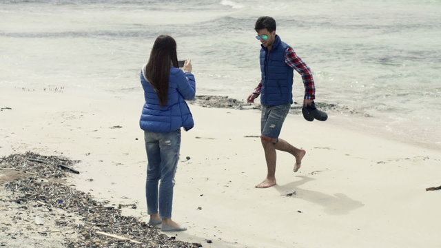 Girlfriend taking photo of her boyfriend on beach
