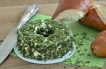 Frischkäse - Doppelrahm mit Schnittlauch und Laugenstange - Brot auf Holz mit Messer