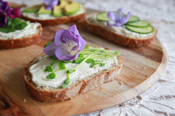 Green sourdough open face sandwiches with purple edible flowers