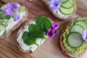 Green sourdough open face sandwiches with purple edible flowers