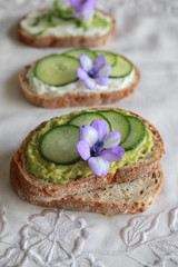 Green sourdough open face sandwiches with purple edible flowers
