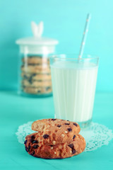 Tasty cookies and glass of milk on table on turquoise background