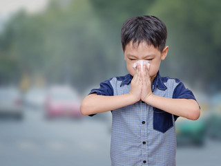 Little Asian boy has allergies from air pollution on street