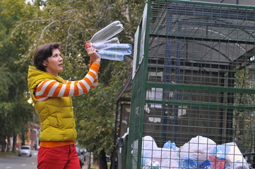 Woman throws plastic bottles to recycling container