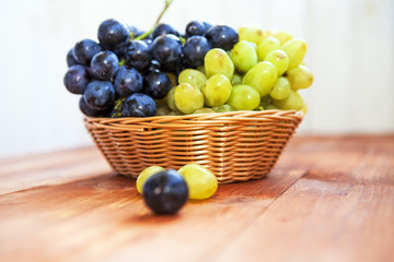 Green and purple round grapes on old wooden table, selective foc