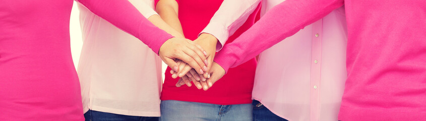 close up of women in pink shirts with hands on top