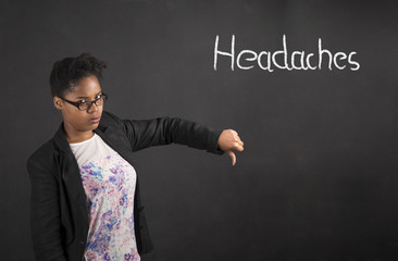 African woman with thumbs down hand signal to headaches on blackboard background
