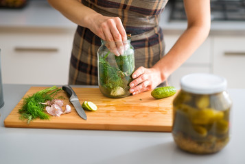 Closeup of woman's hands preparing cucumbers for dill pickles