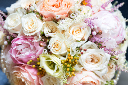 Elegant bridal bouquet of roses in light colors and pearl beads decoration.