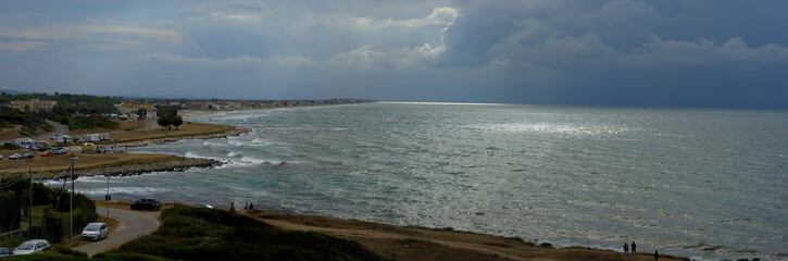 Approaching storm on a beach of Gargano. The sun filters through a hole in the clouds and stormy
