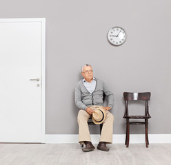 Bored senior gentleman sitting in an office lobby