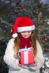 Smiling  little girl with christmas gift in the winter forest