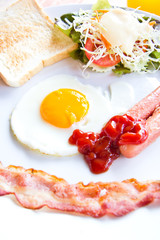 fried eggs with bacon, sausages and toasts on white plate