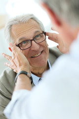 Senior man trying new eyeglasses on, optical store