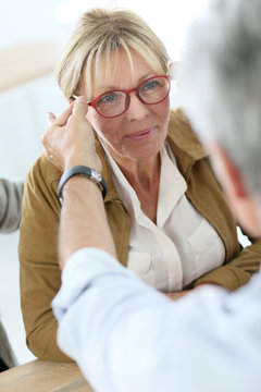 Senior woman trying new eyeglasses on, optical store